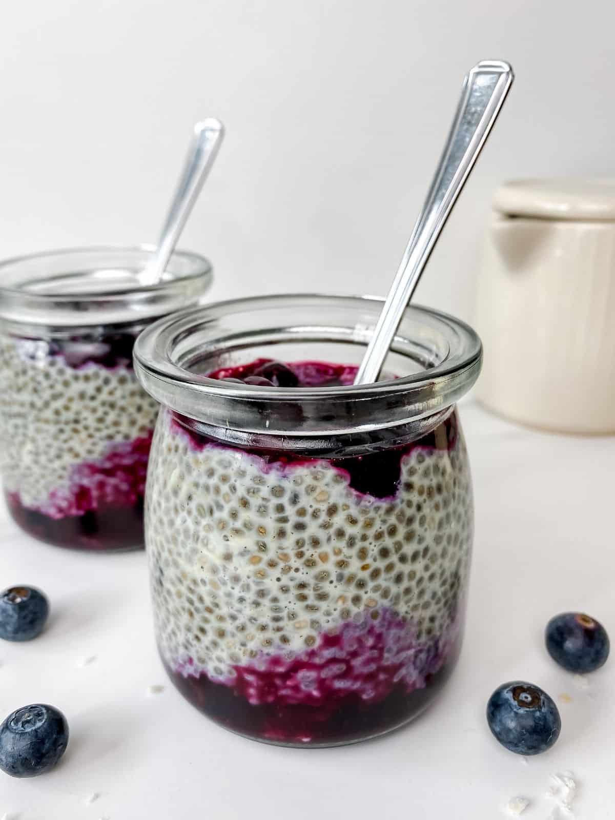 cardamom chia pudding in two glass jars with a jug in the background.
