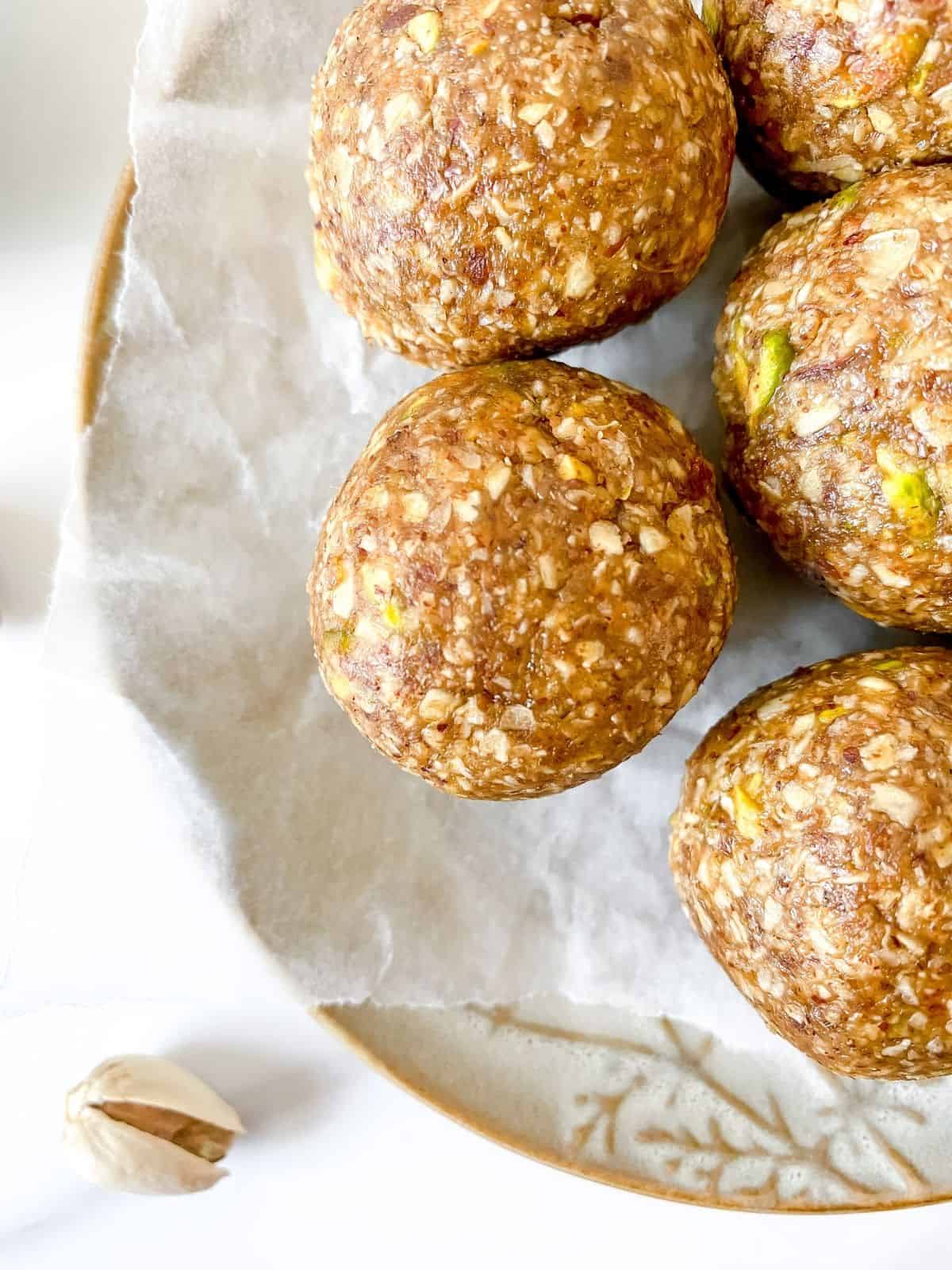 cardamom pistachio energy balls on a brown plate.