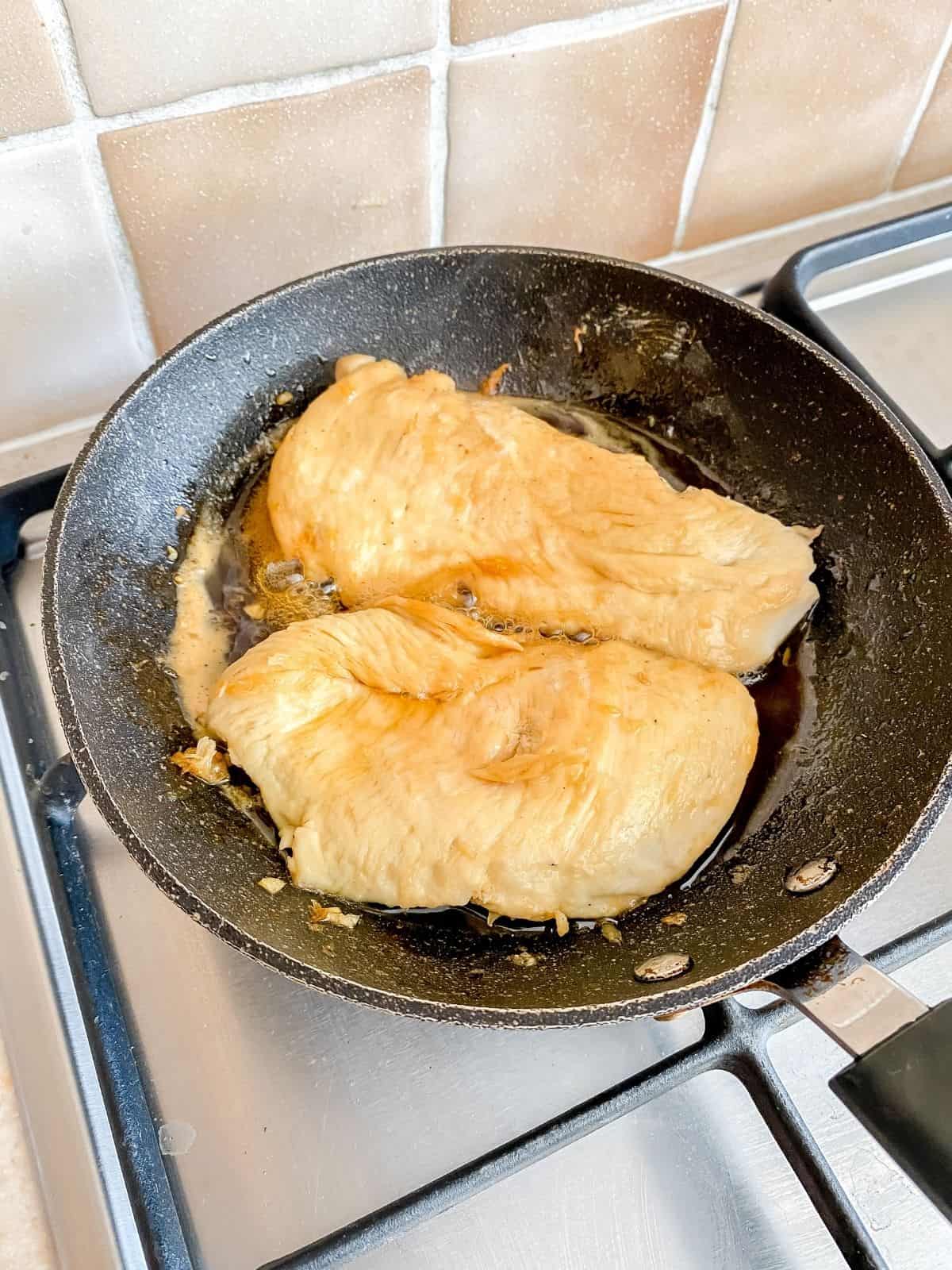chicken breasts frying in a pan.