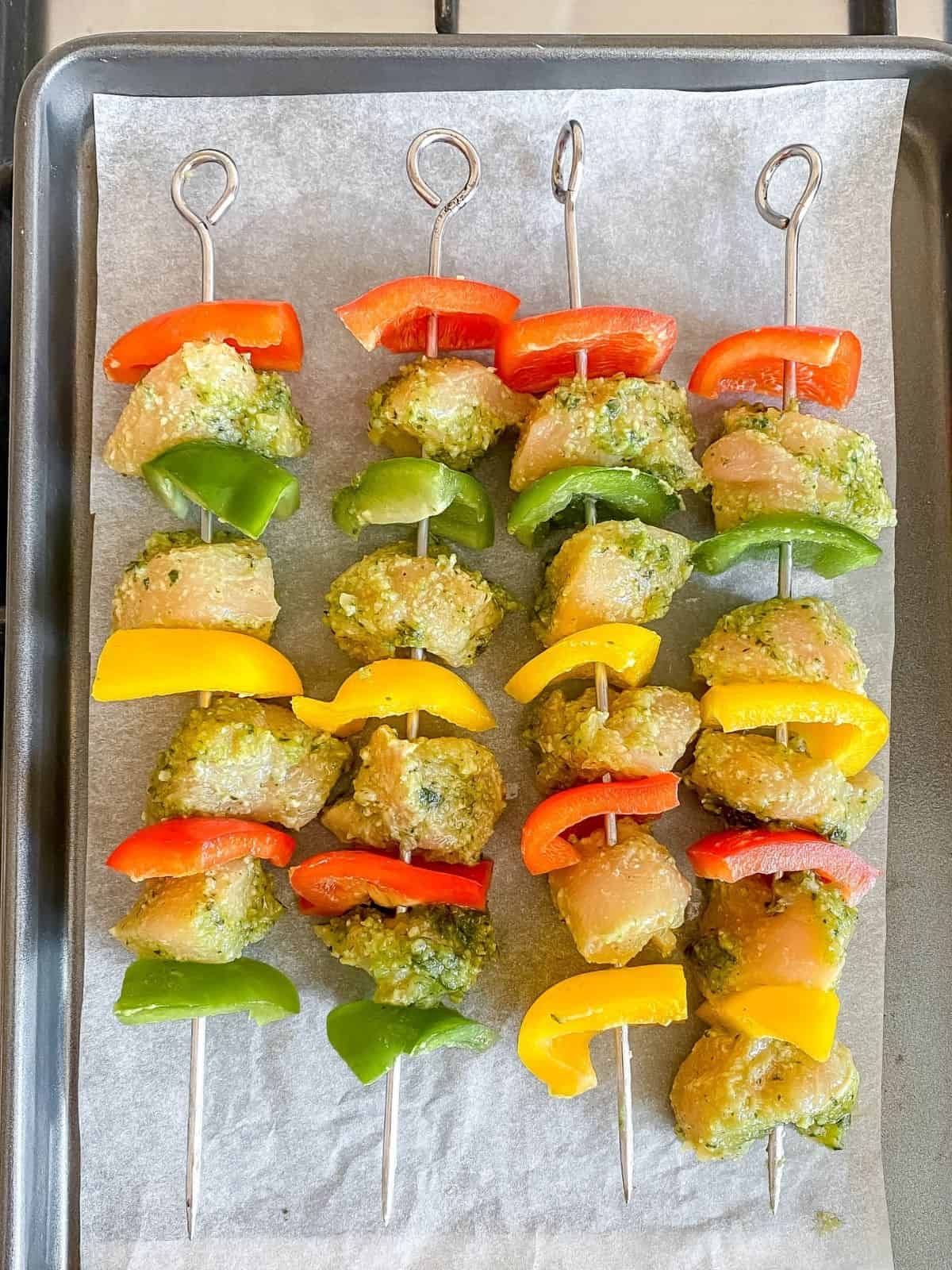 pesto chicken skewers on a baking tray.
