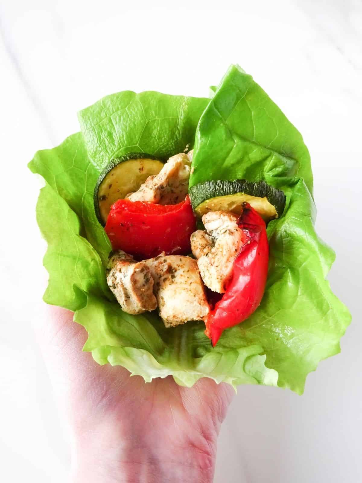 coconut marinated chicken with bell peppers in a lettuce wrap.