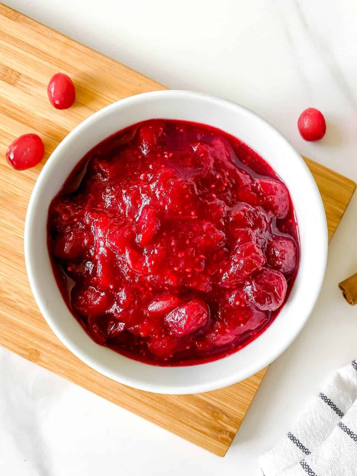citrus free cranberry sauce in a white bowl on a wooden board.