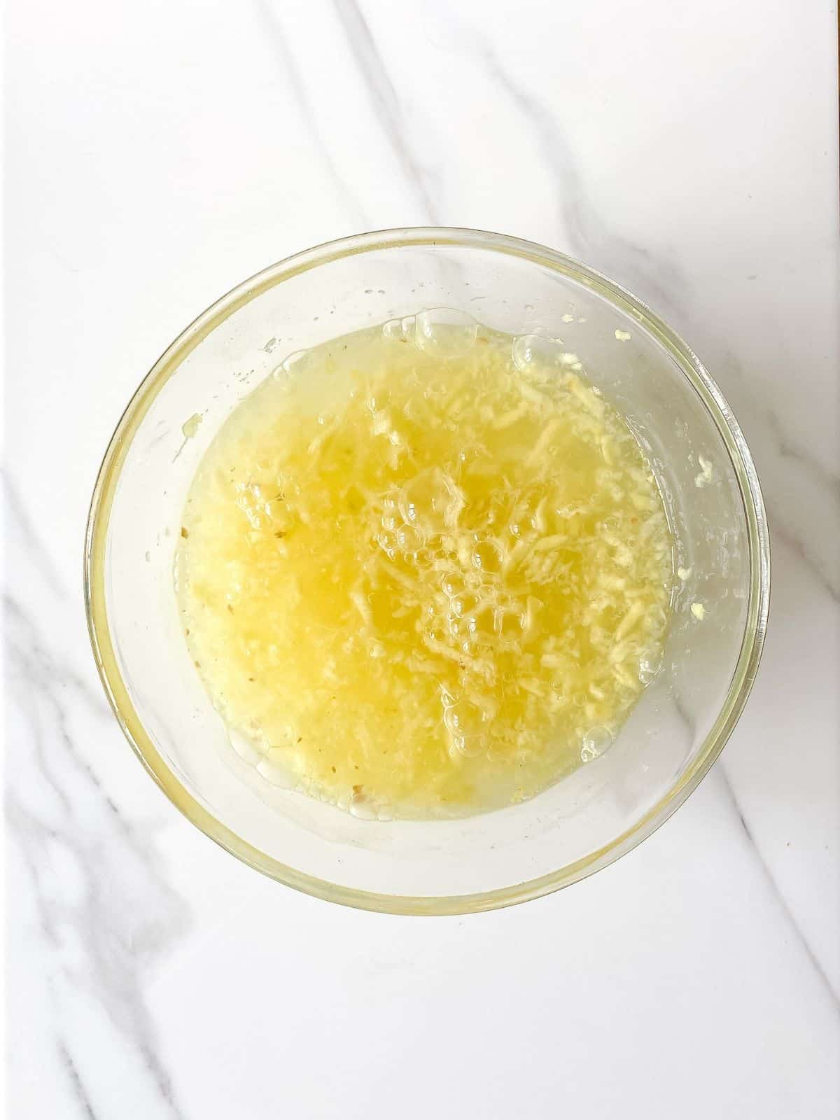 fresh grated ginger and sparkling water in a glass bowl.