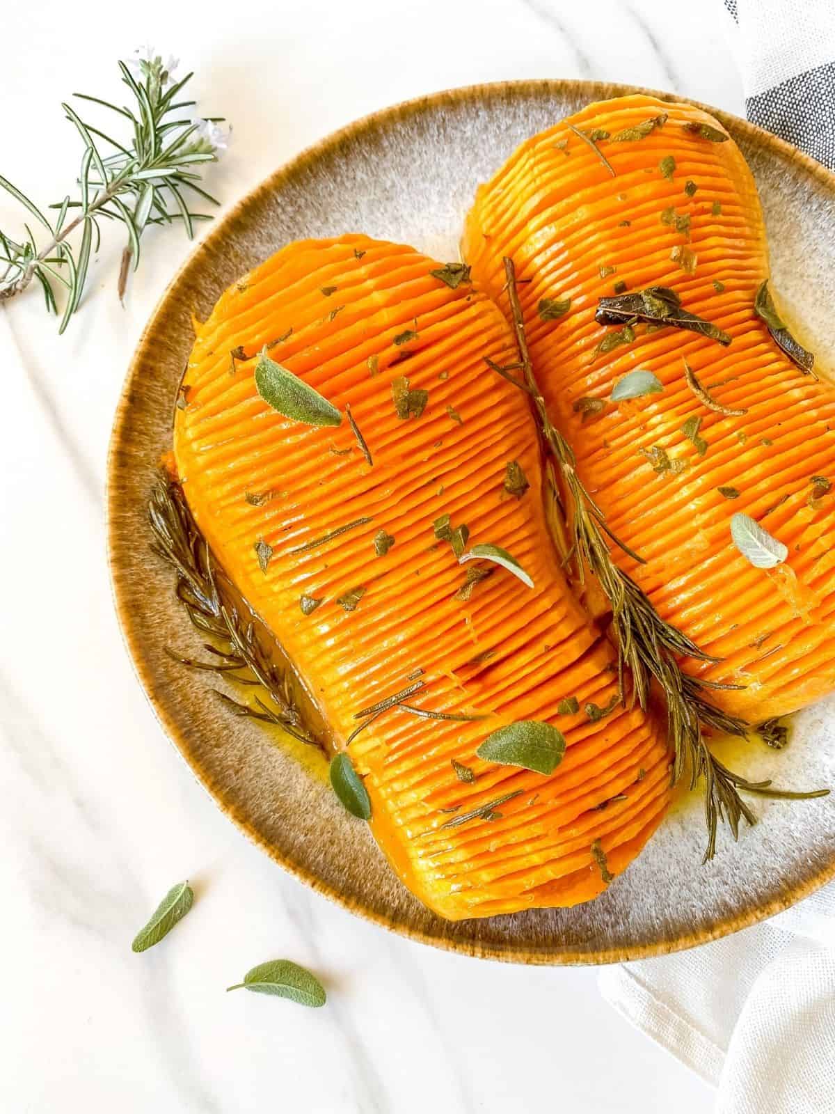hasselback butternut squash with maple brown butter on a grey and brown plate.
