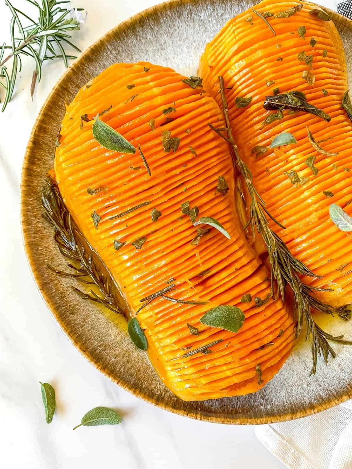 hasselback butternut squash with maple brown butter on a grey and brown plate.
