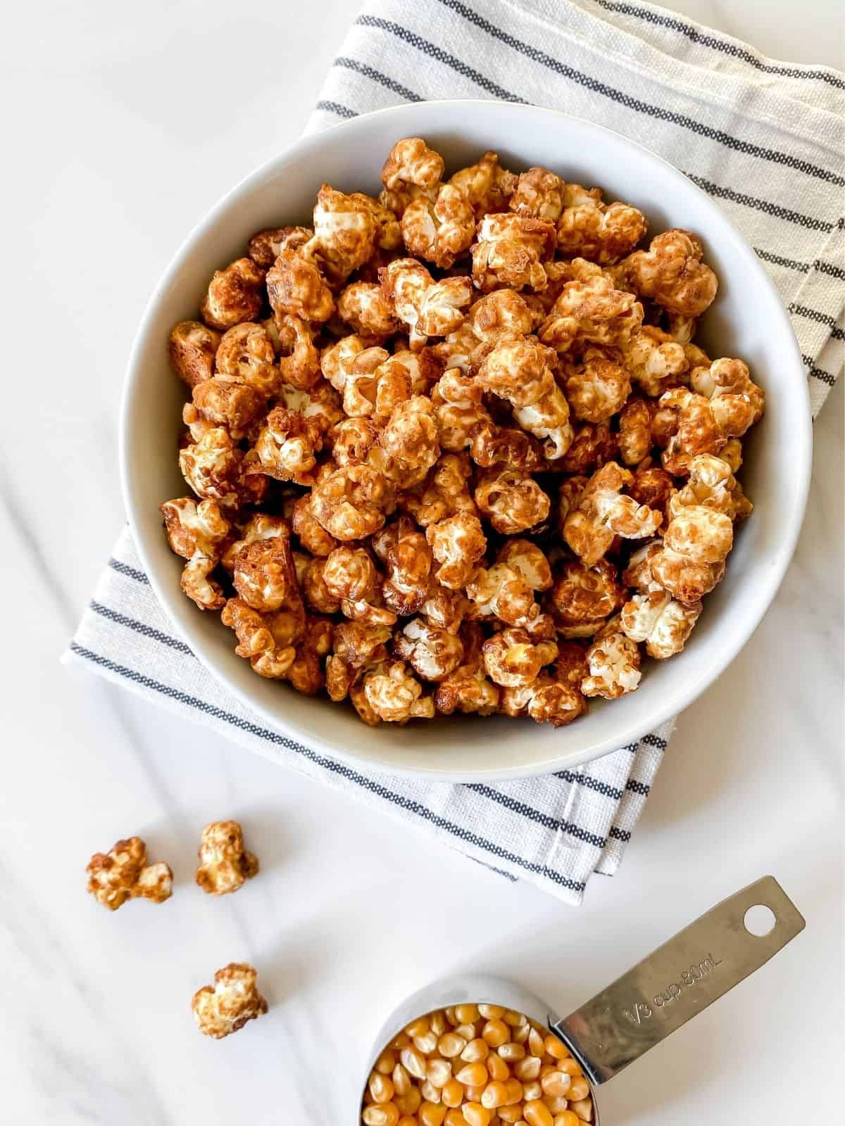 maple syrup popcorn in a white bowl on a striped cloth.