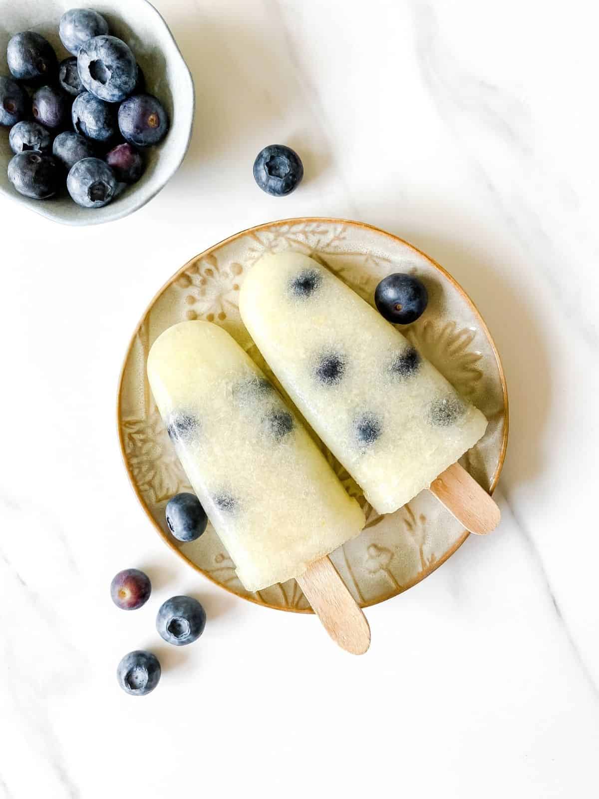 melon blueberry popsicles on a brown plate.