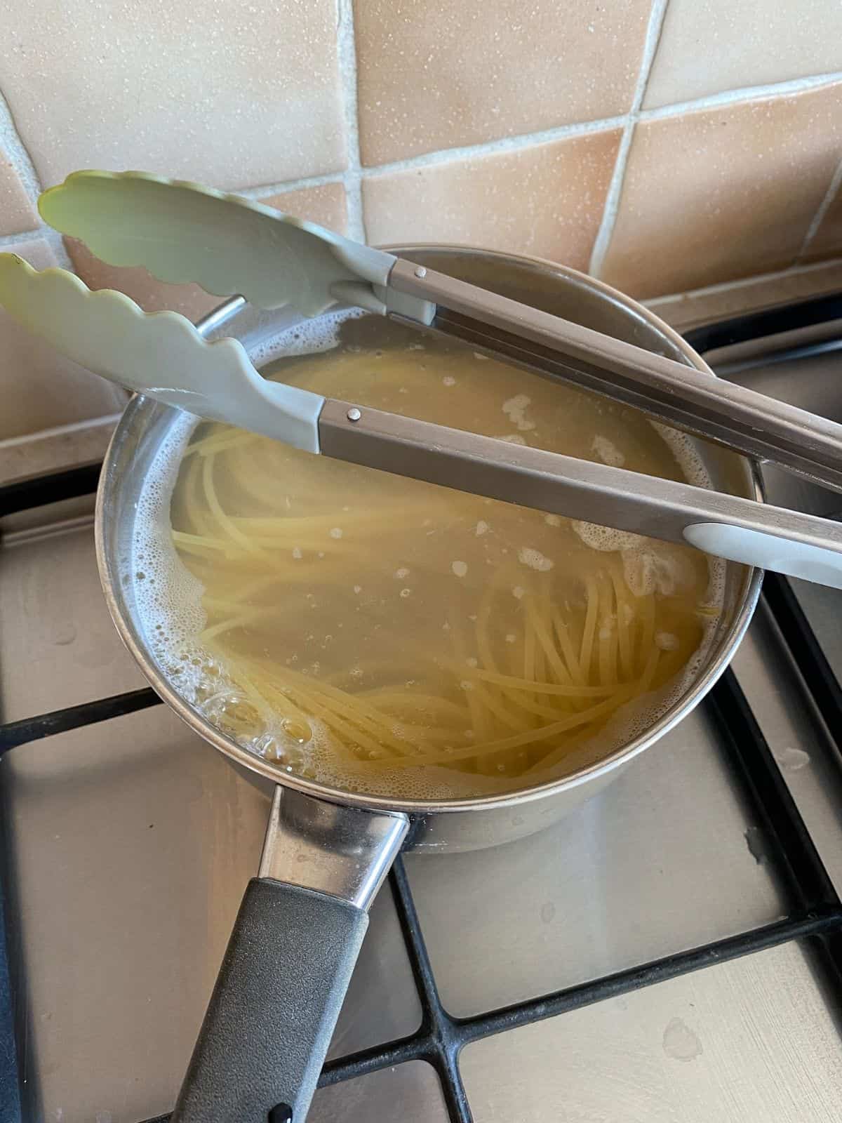 spaghetti cooking in a pan.
