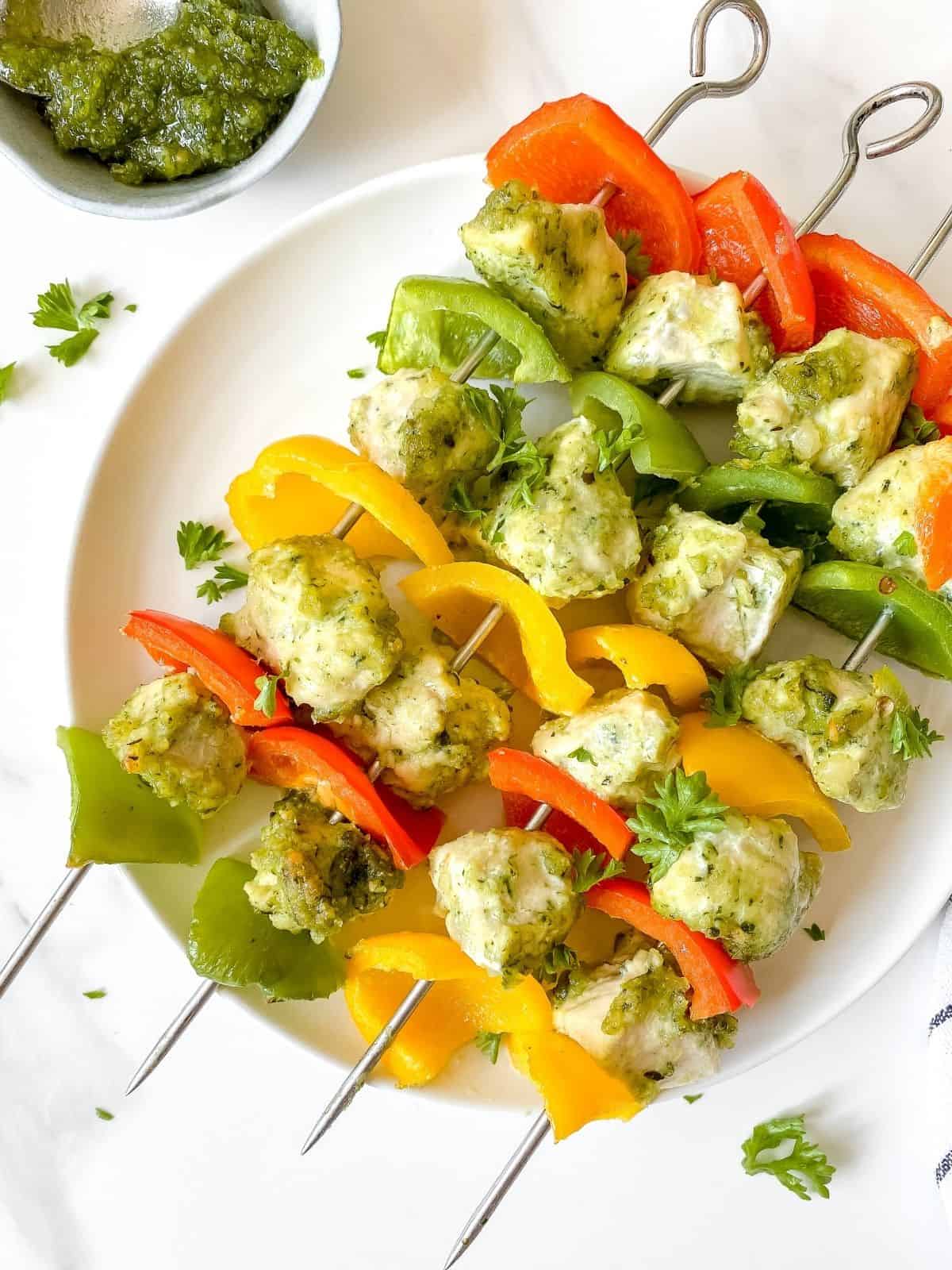pesto chicken skewers on a white plate.