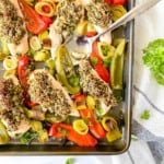 pesto chicken tray bake on a white and blue striped cloth.