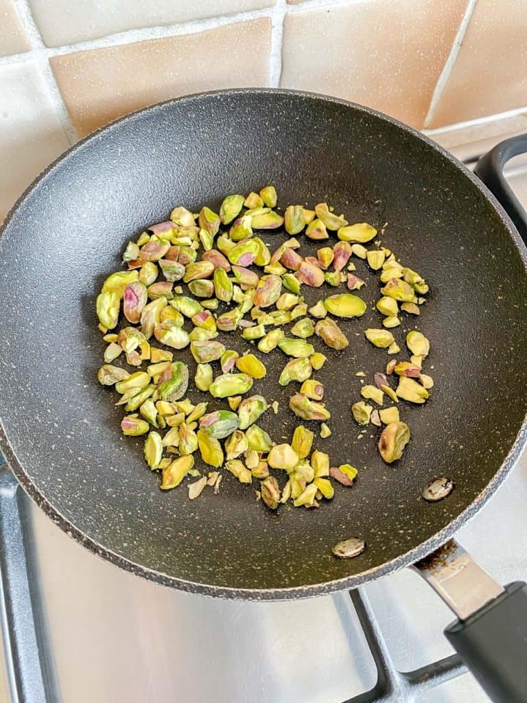 pistachios in a black pan on a stove top.