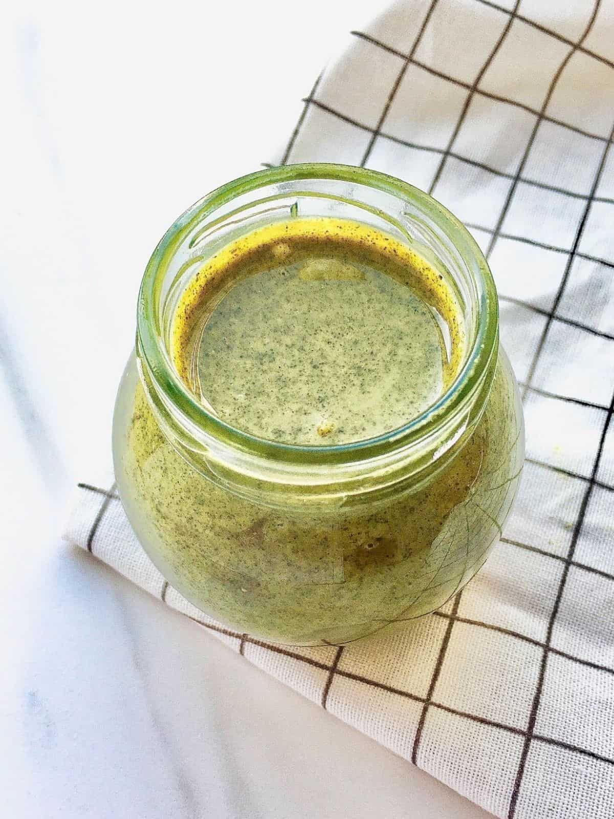 glass jar of pumpkin seed butter on a checked cloth.