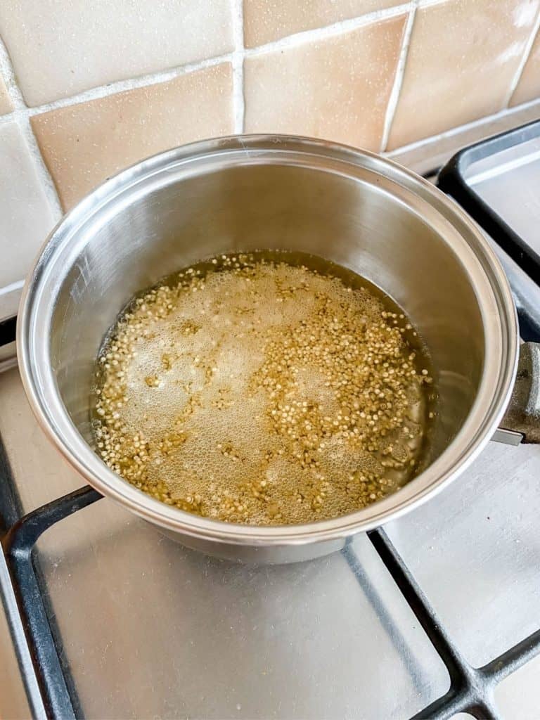 quinoa boiling in a pan on a stove top.