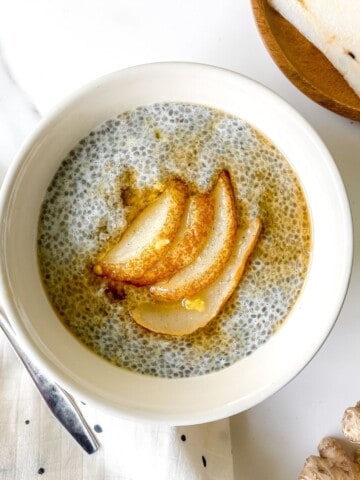 spiced pear chia pudding in a white bowl on a spotty cloth.