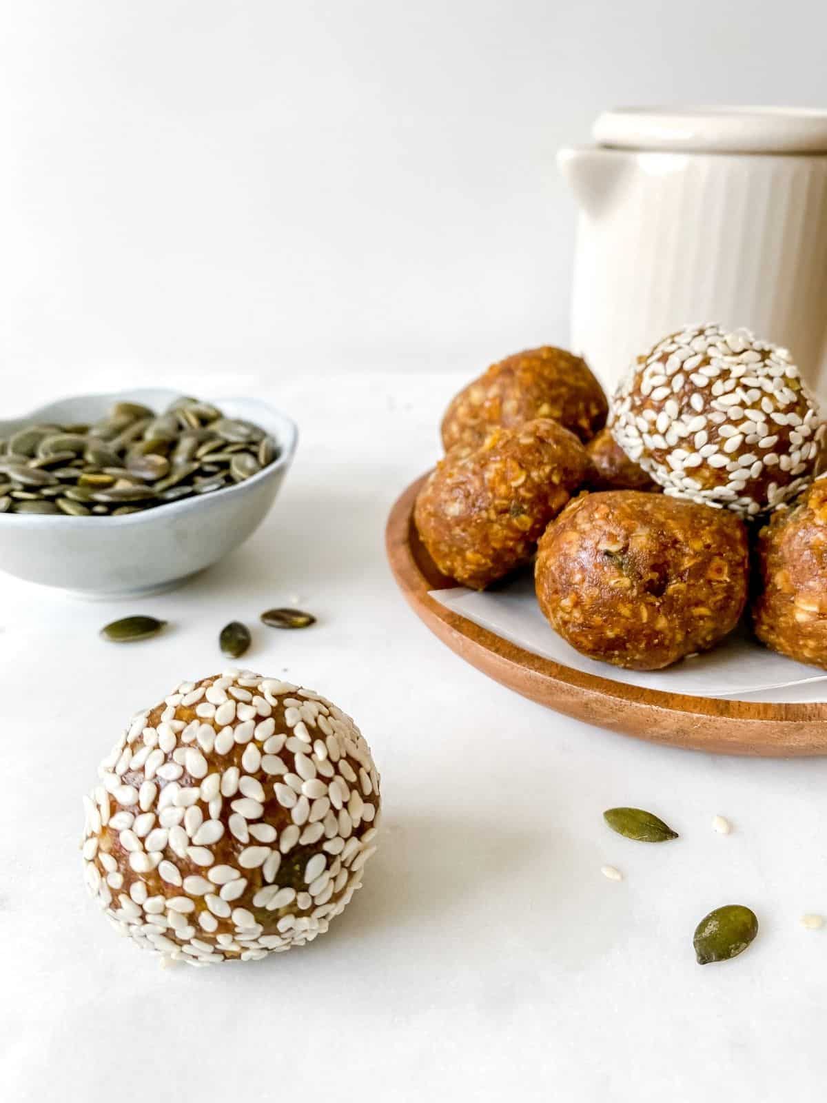 turmeric ginger energy balls with a jug and bowl of pumpkin seeds in the background.