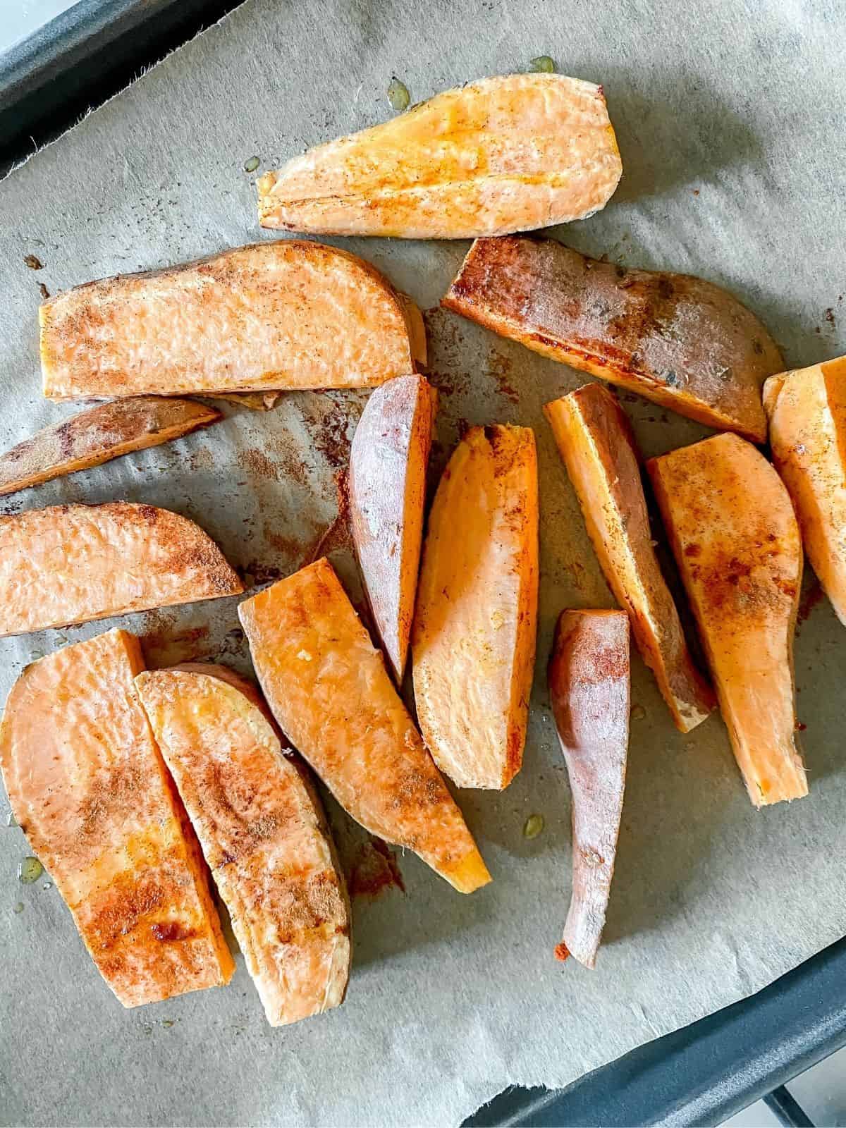 uncooked sweet potato wedges on a baking tray.