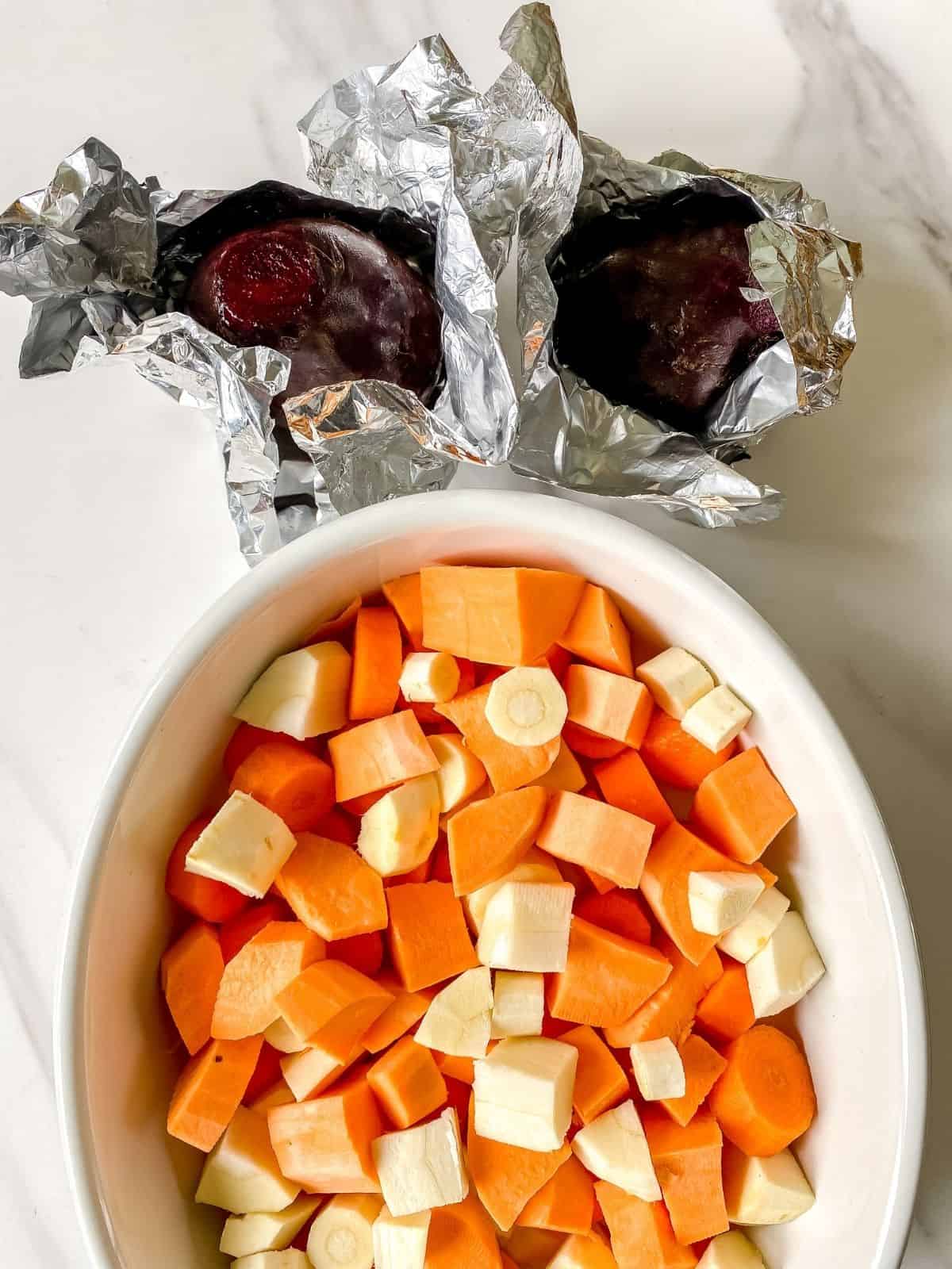 beets in foil next to a dish of vegetables.