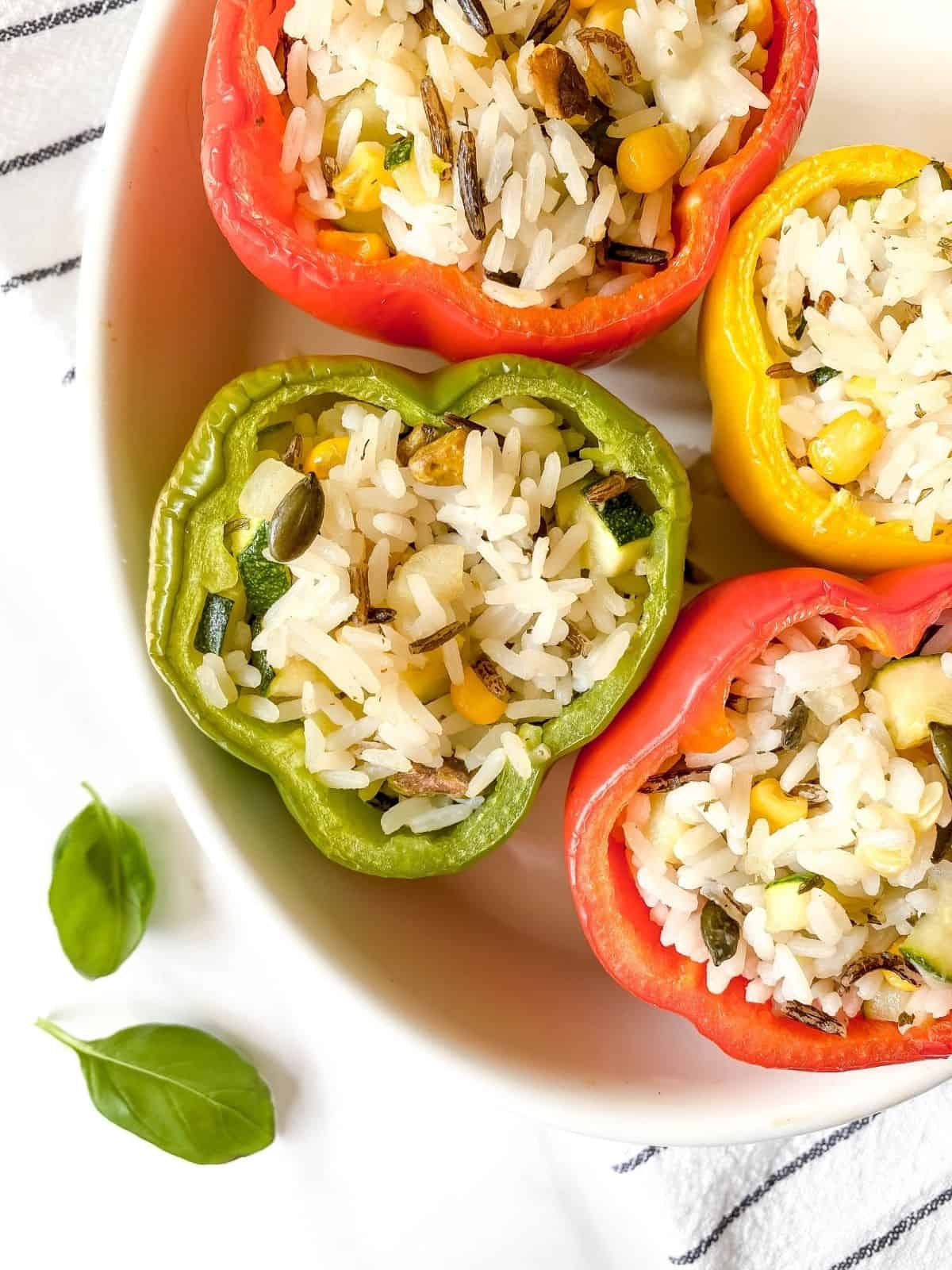 different coloured wild rice stuffed peppers in a white baking dish.