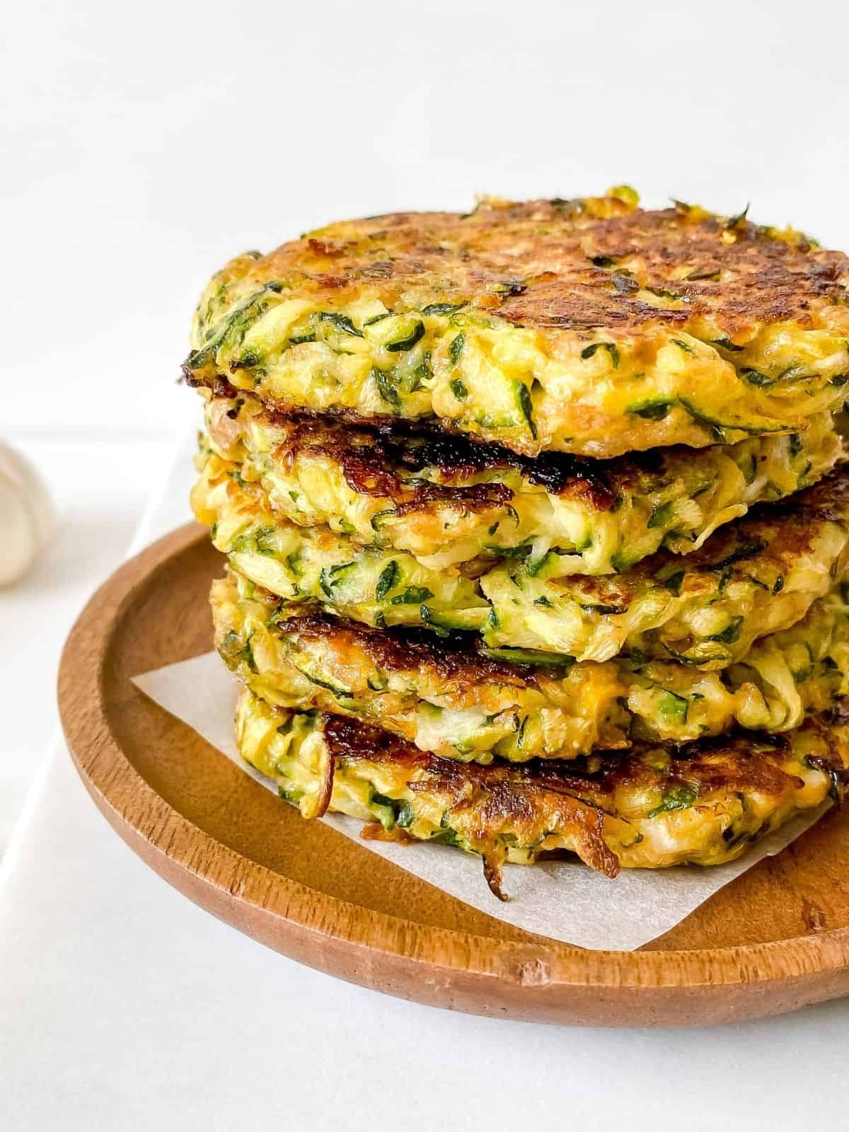 stack of zucchini and mascarpone fritters on a wooden plate.
