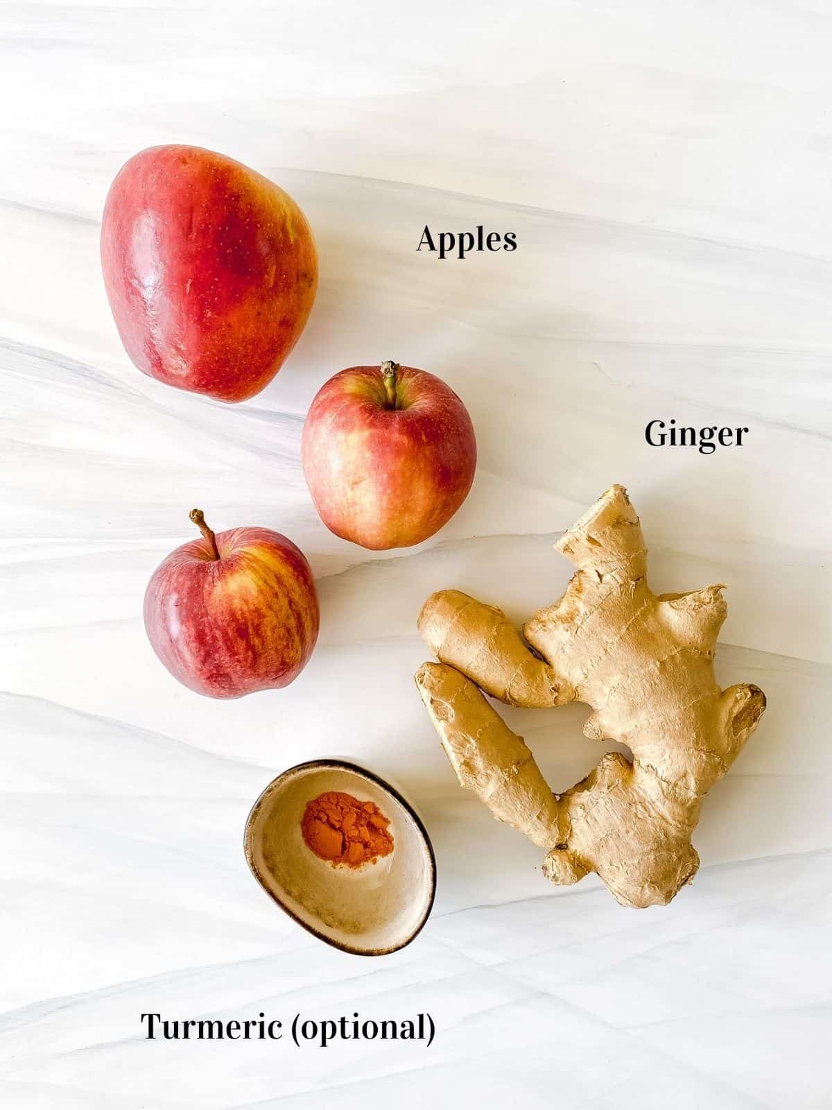 three apples, ginger and a small bowl of turmeric.