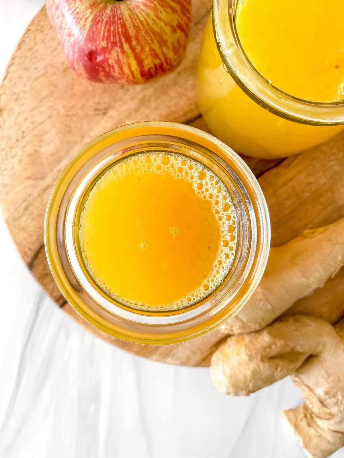 apple ginger juice in two glass jars on a wooden board.