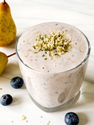 blueberry pear smoothie in a glass with pears in the background.