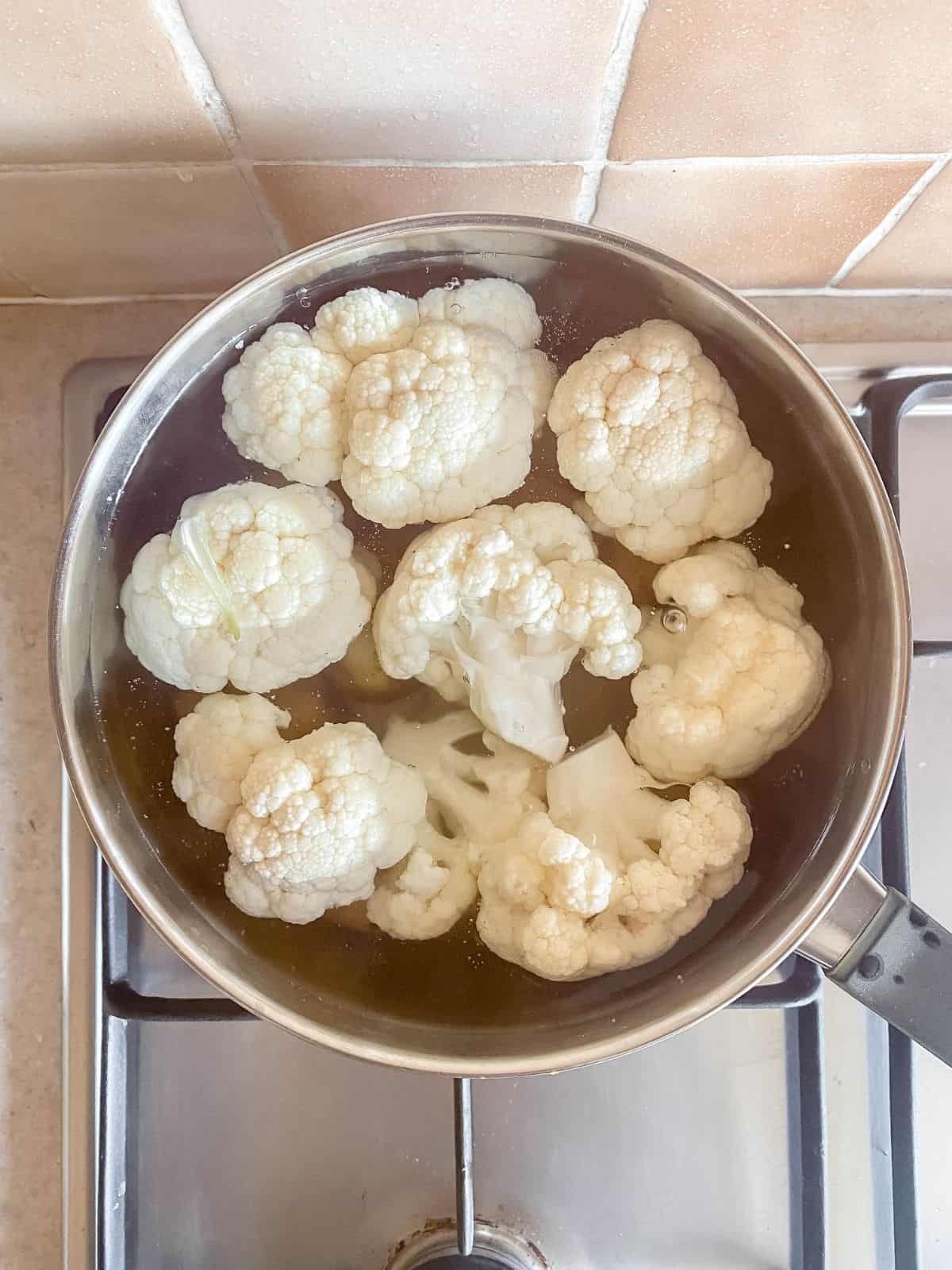 cauliflower florets and potatoes in a pan of water.