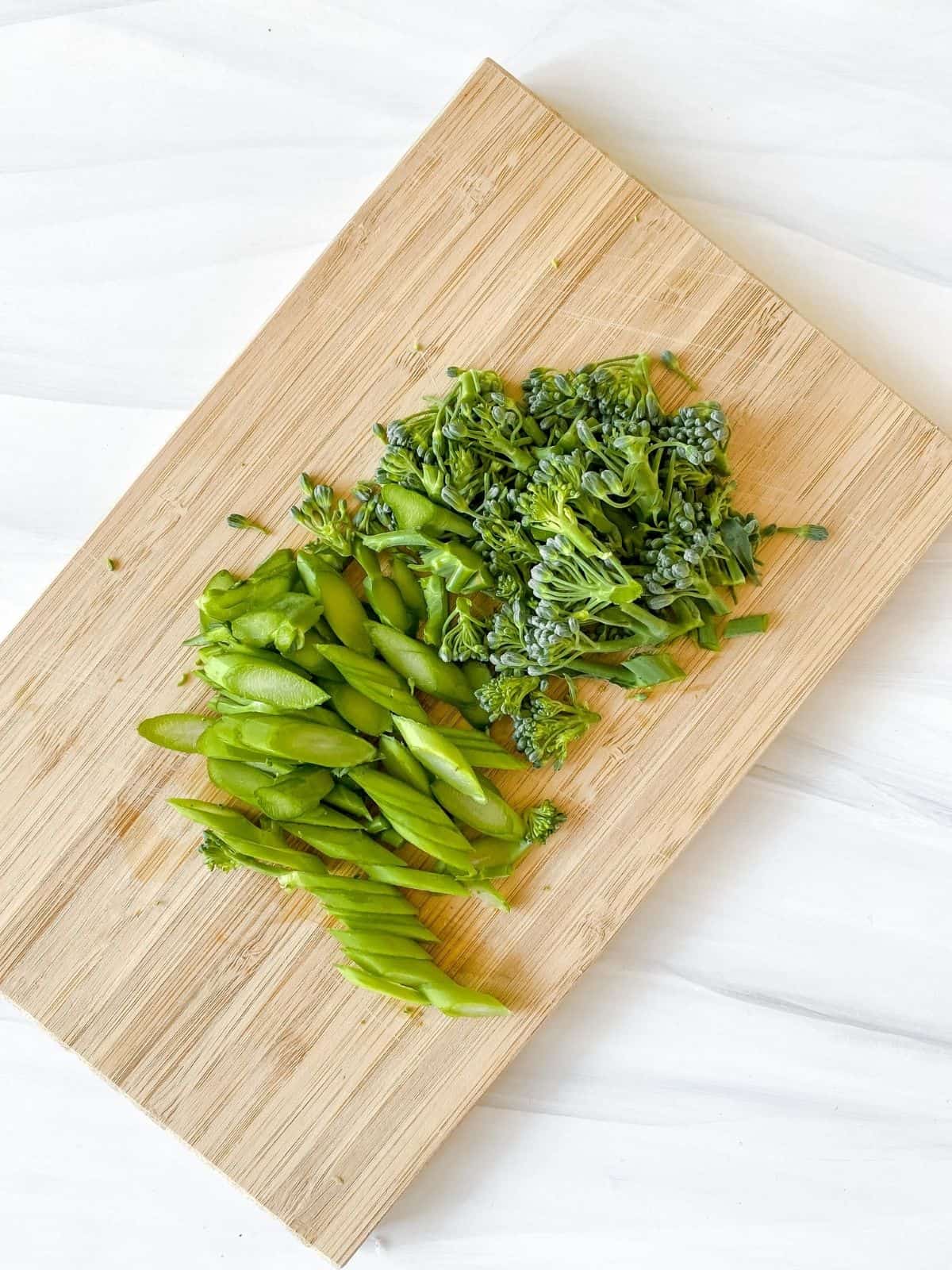 diced broccolini on a wooden board.