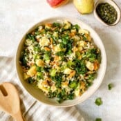 kale wild rice salad in a brown bowl on a striped cloth.
