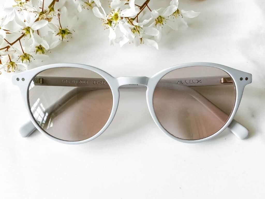 Avulux migraine glasses next to white flowers.