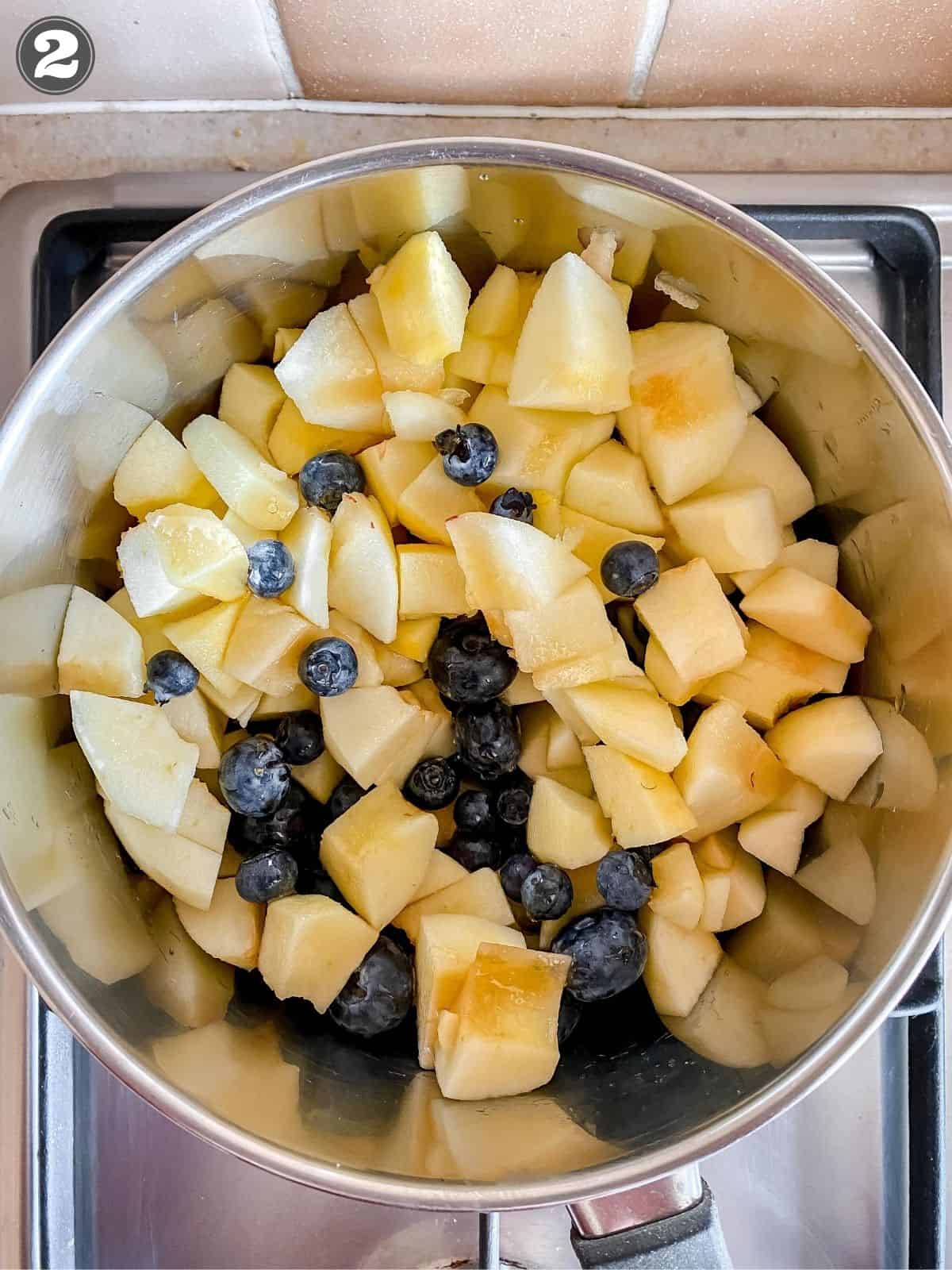 apples and blueberries in a pan before being cooked.