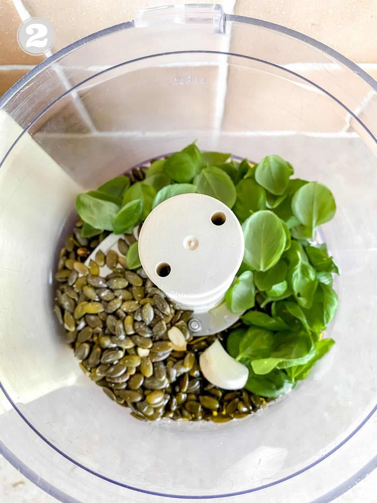 pumpkin seeds, garlic and basil leaves in a food processor labelled number two.