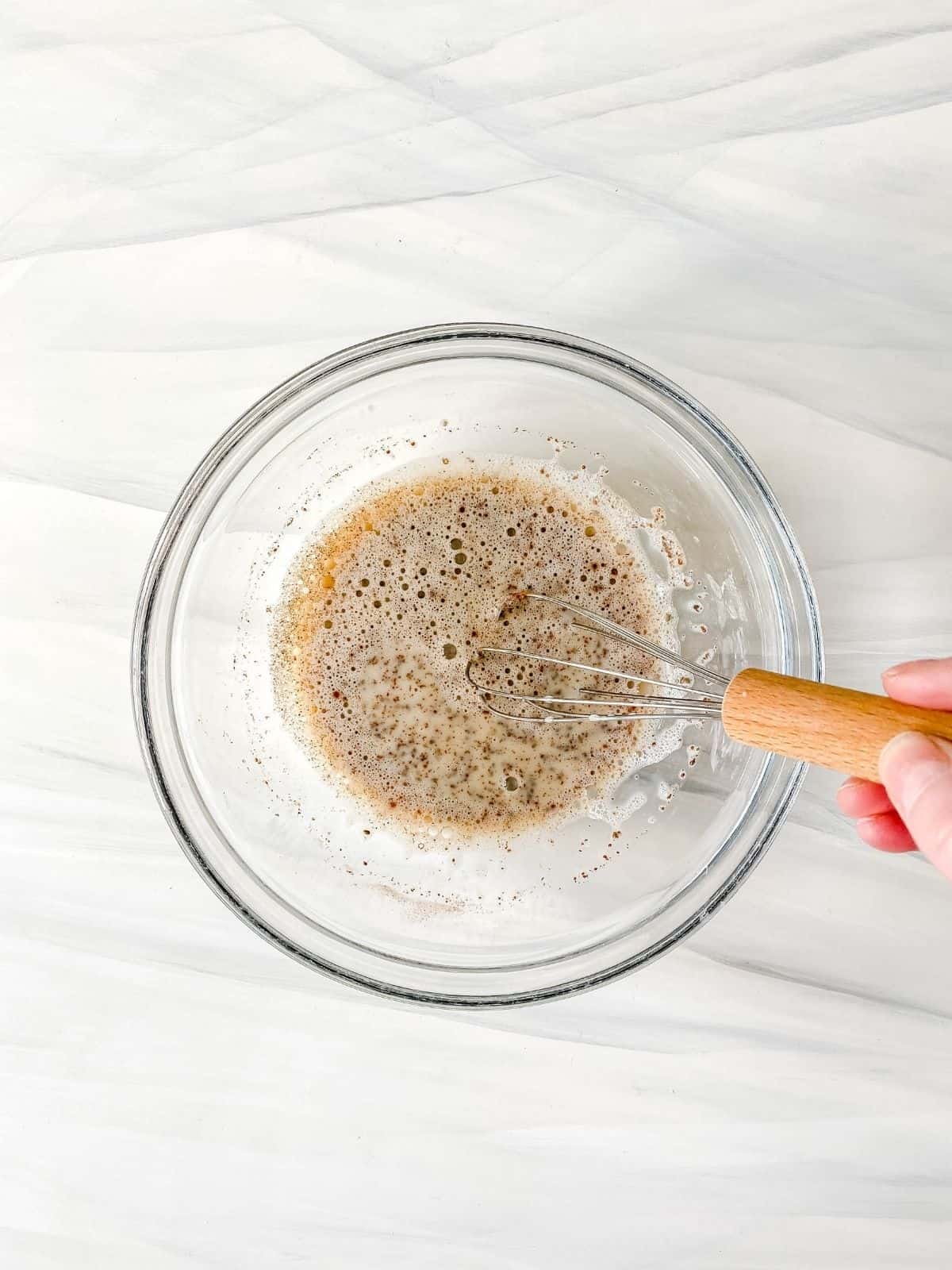 chia pudding mixed in a glass bow with a whisk.
