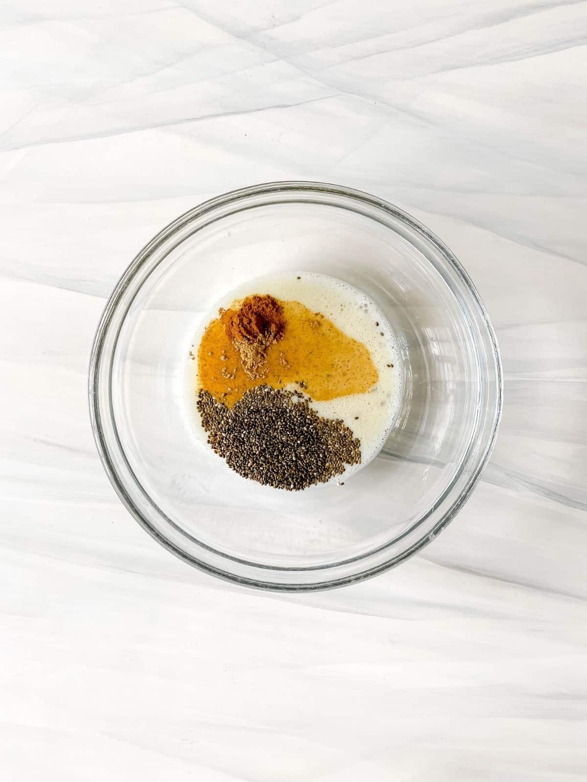 chia seeds, non-dairy milk and spices in a glass bowl.