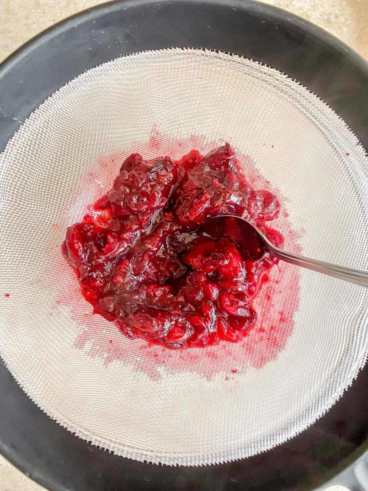 cranberries in a sieve with a spoon in it.