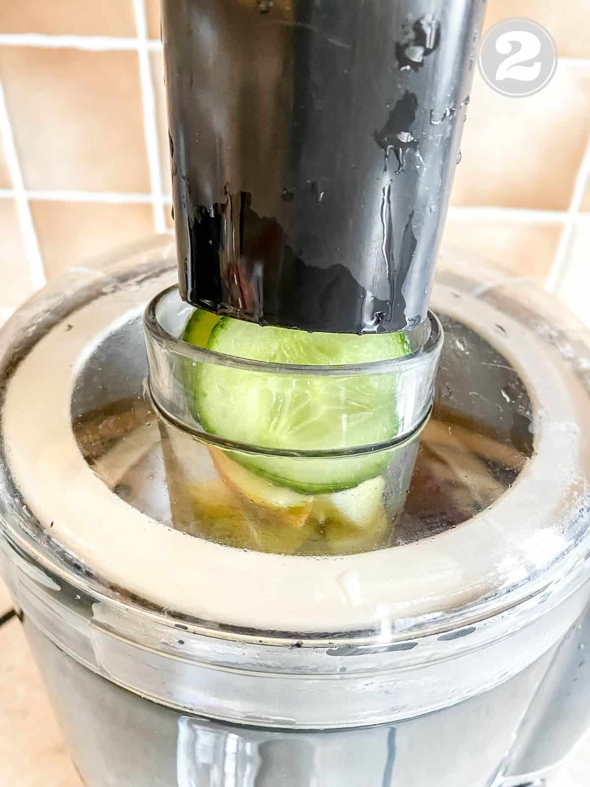 cucumber being pressed through a juicer.