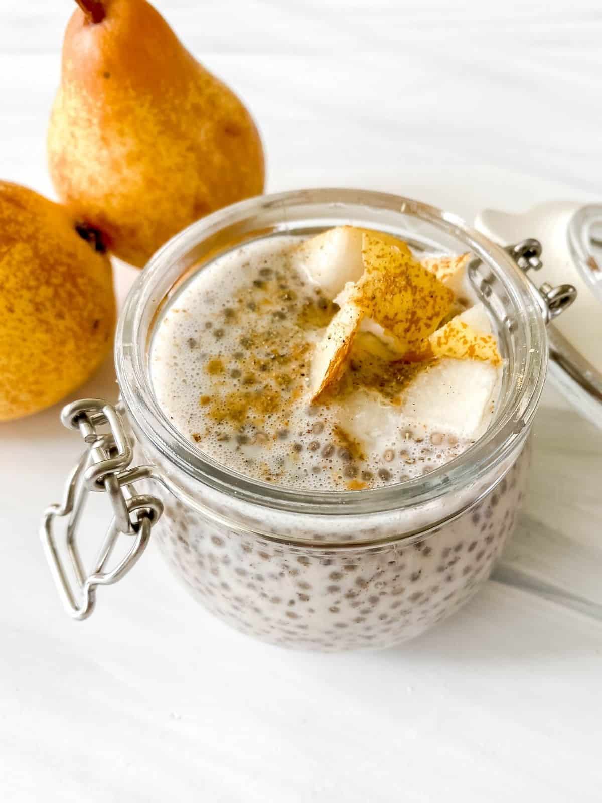 gingerbread chia pudding in a glass jar with pears in the background.
