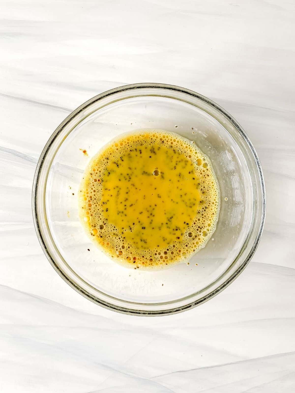 chia seeds whisked into milk with turmeric powder in a glass bowl.