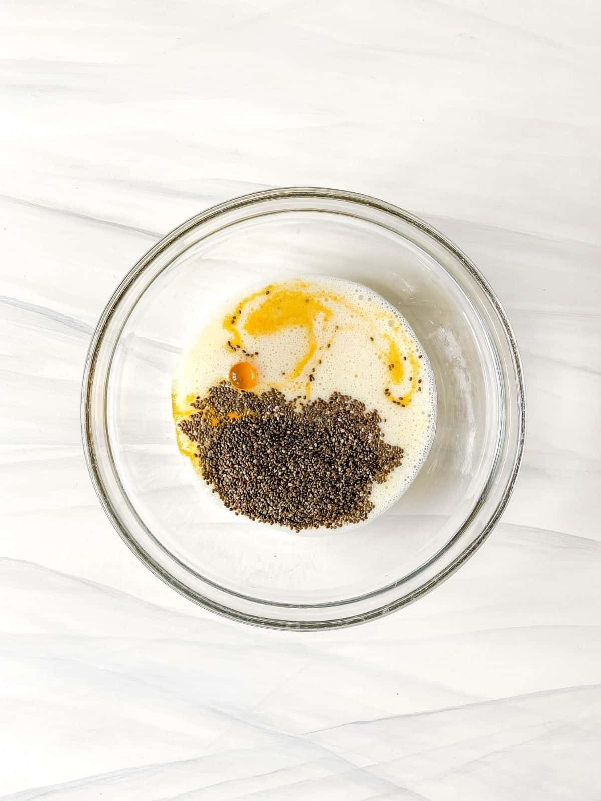 non-dairy milk, chia seeds and turmeric in a glass bowl.