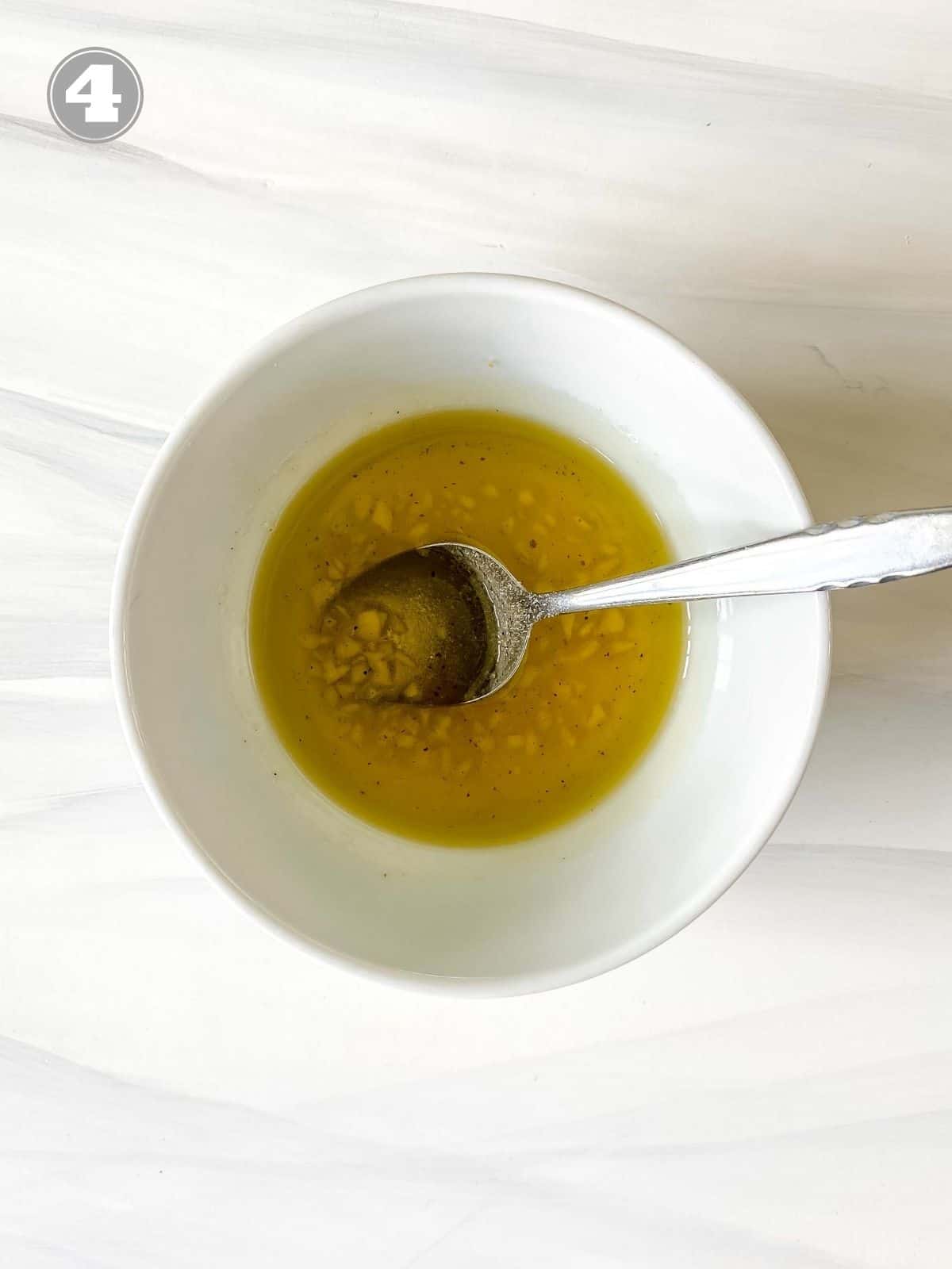 honey dressing in a white bowl with a spoon in it.