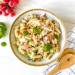 turkey pasta salad in a grey bowl with a brown rim next to a bunch of radishes.