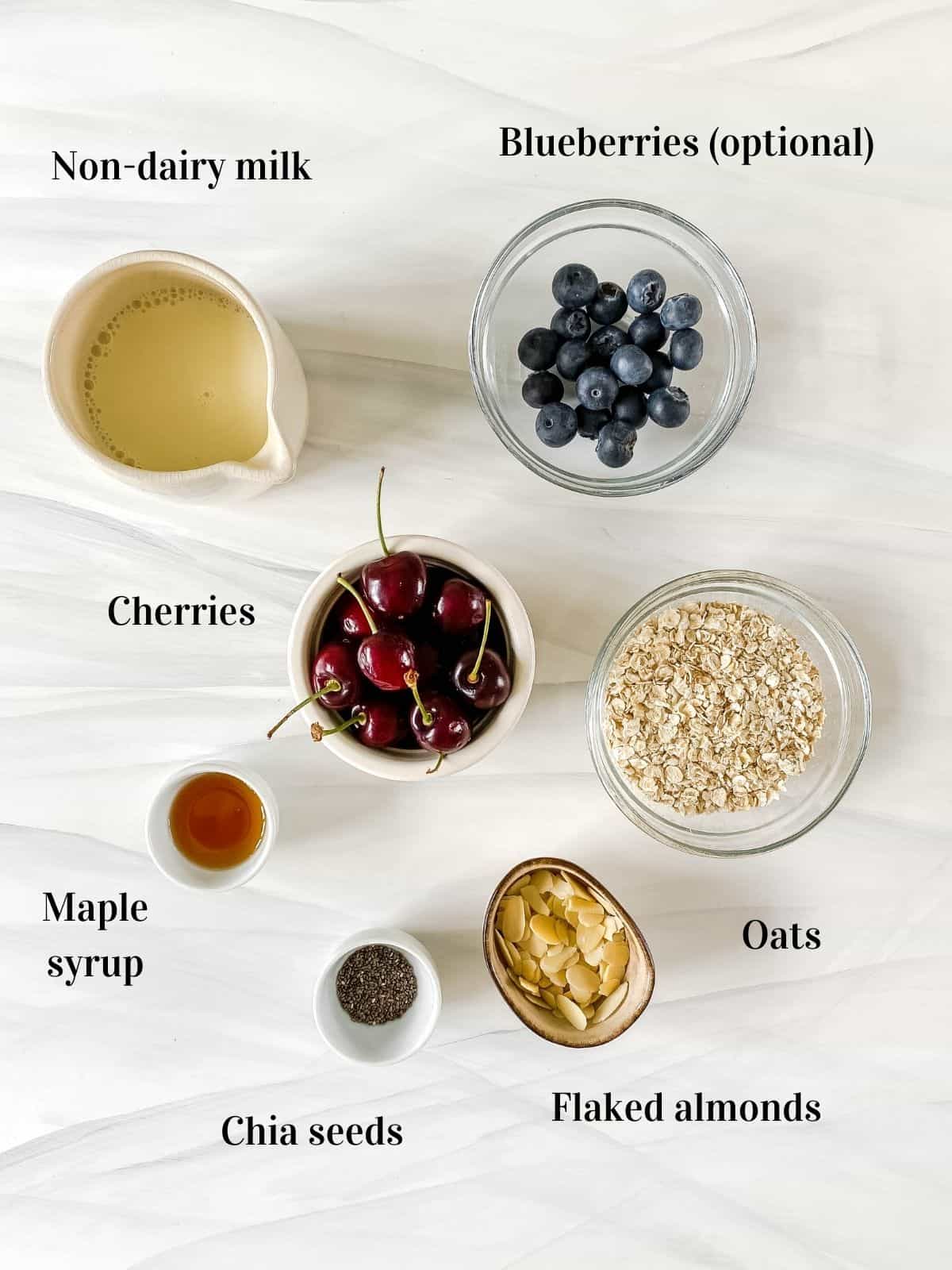 all the ingredients for cherry overnight oats in small bowls.