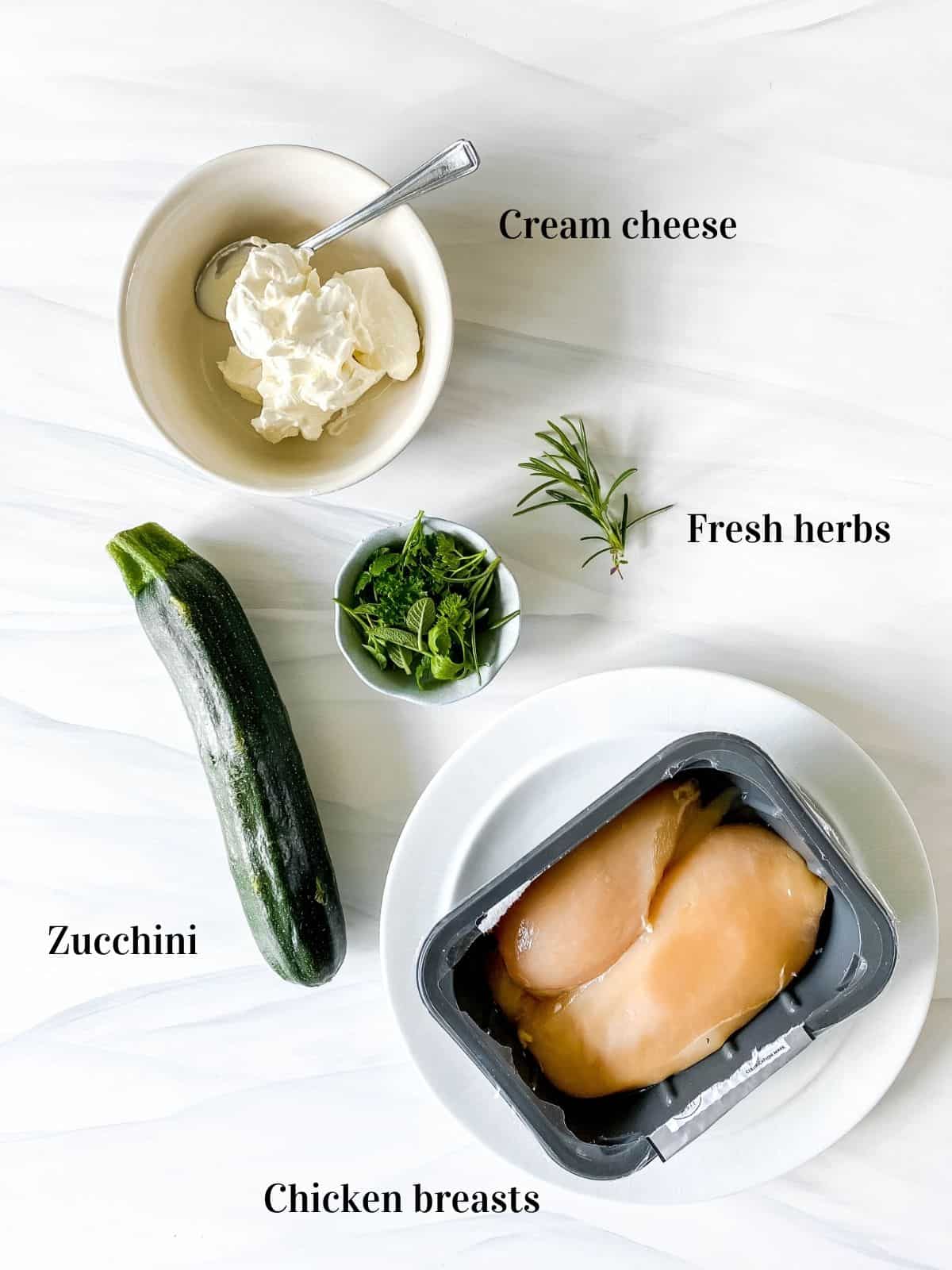 chicken breasts, zucchini, herbs and cream cheese in a bowl with a spoon in it.