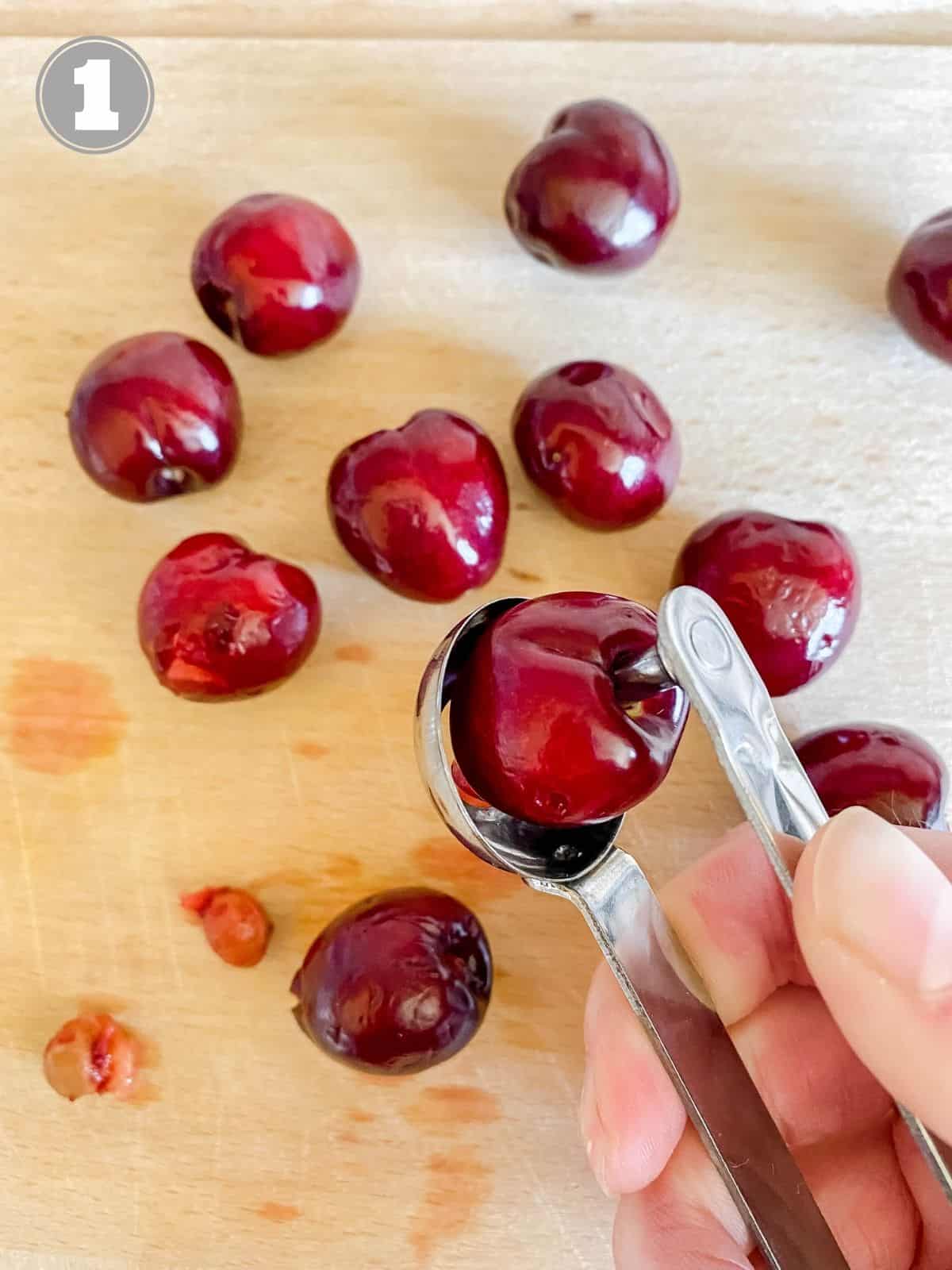 cherries being pitted on a wooden chopping board.