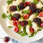 cherry caprese salad on a white plate on a blue cloth.