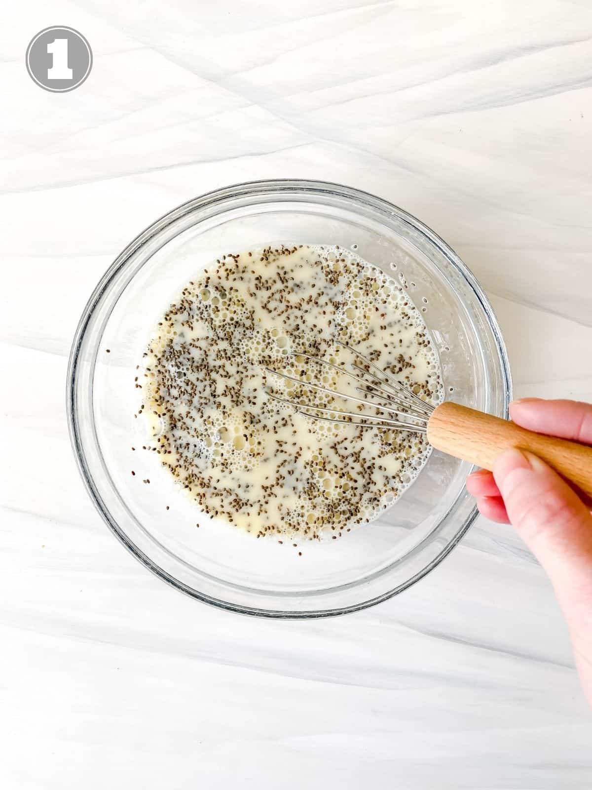 chia pudding being whisked in a glass bowl.