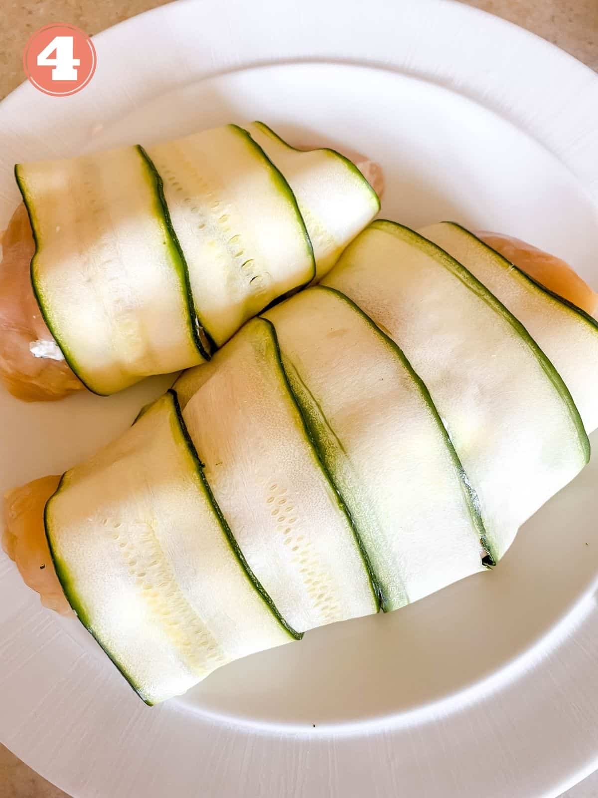 chicken breasts wrapped in zucchini on a white plate.