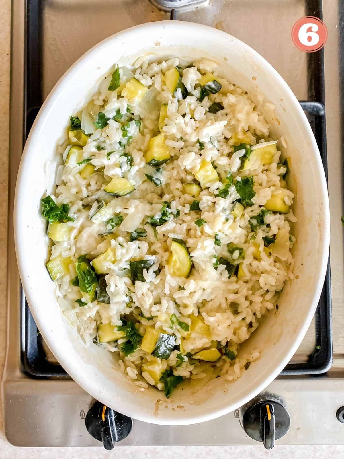 cooked zucchini risotto in a white dish on a stove top labelled number six.