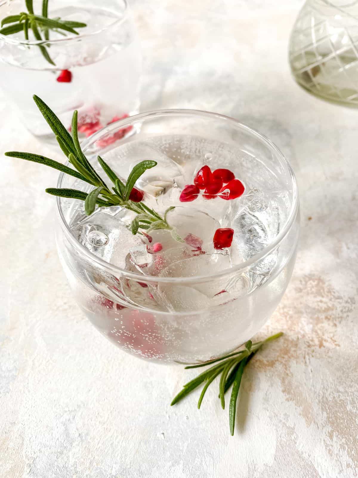 two glasses of elderflower cordial mocktail with pomegranate and rosemary.