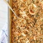 maple coconut granola on a baking tray with a spoon on it.
